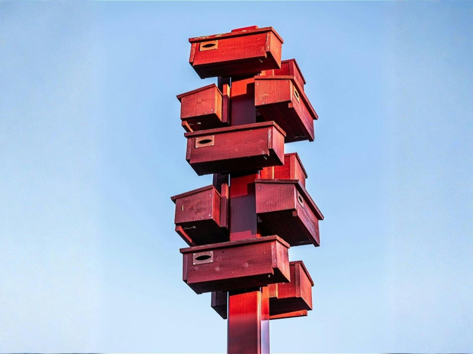 a bunch of red mailboxes stacked clustered on a pole