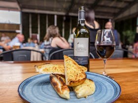 Garlic bread on a plate with a bottle of wine