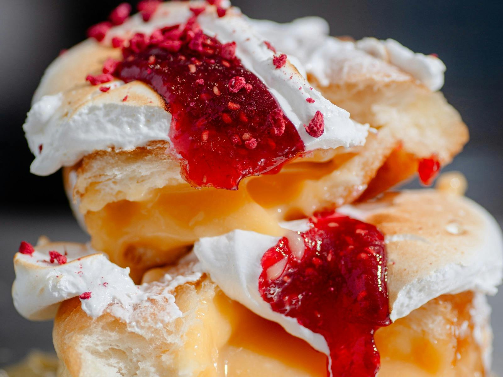 Lemon raspberry meringue doughnut cut in half.