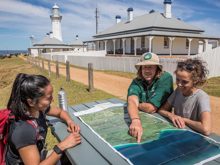 Guide showing guests places on a map of the Light to Light walk outside a lighthouse