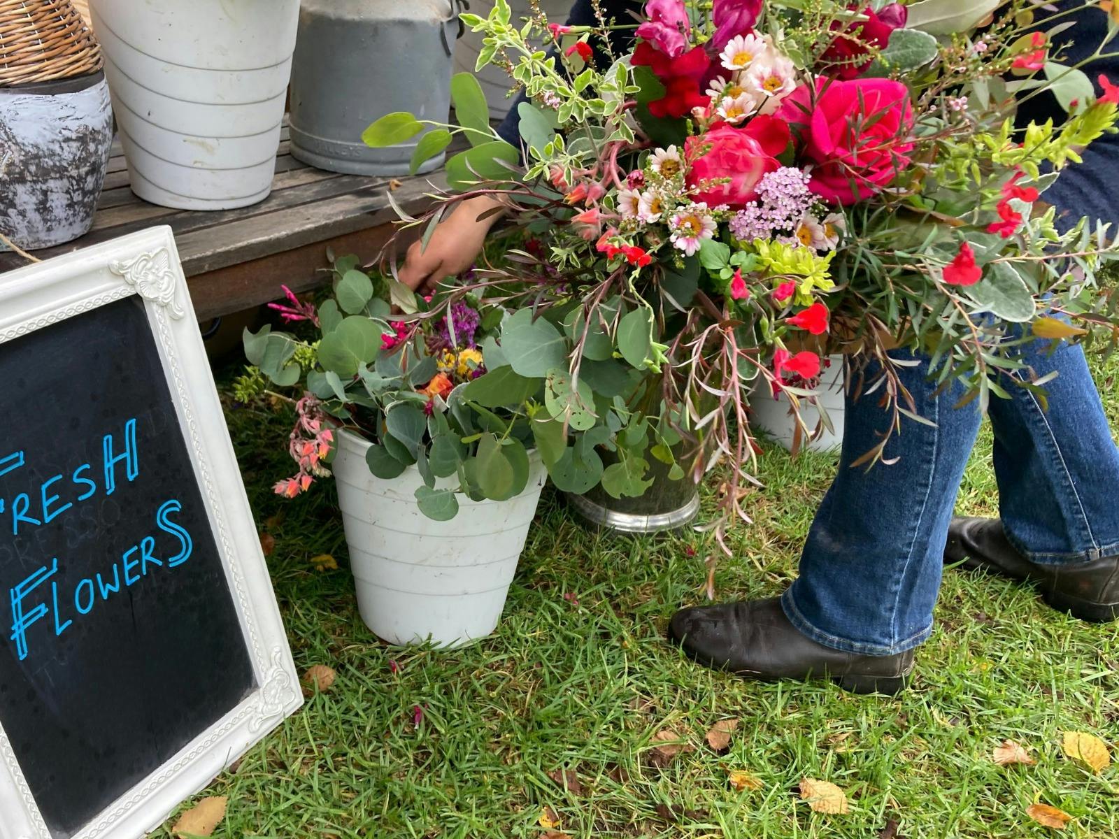 Large bunch of flowers being taken from a bucket next to a sign that says 'Fresh Flowers'