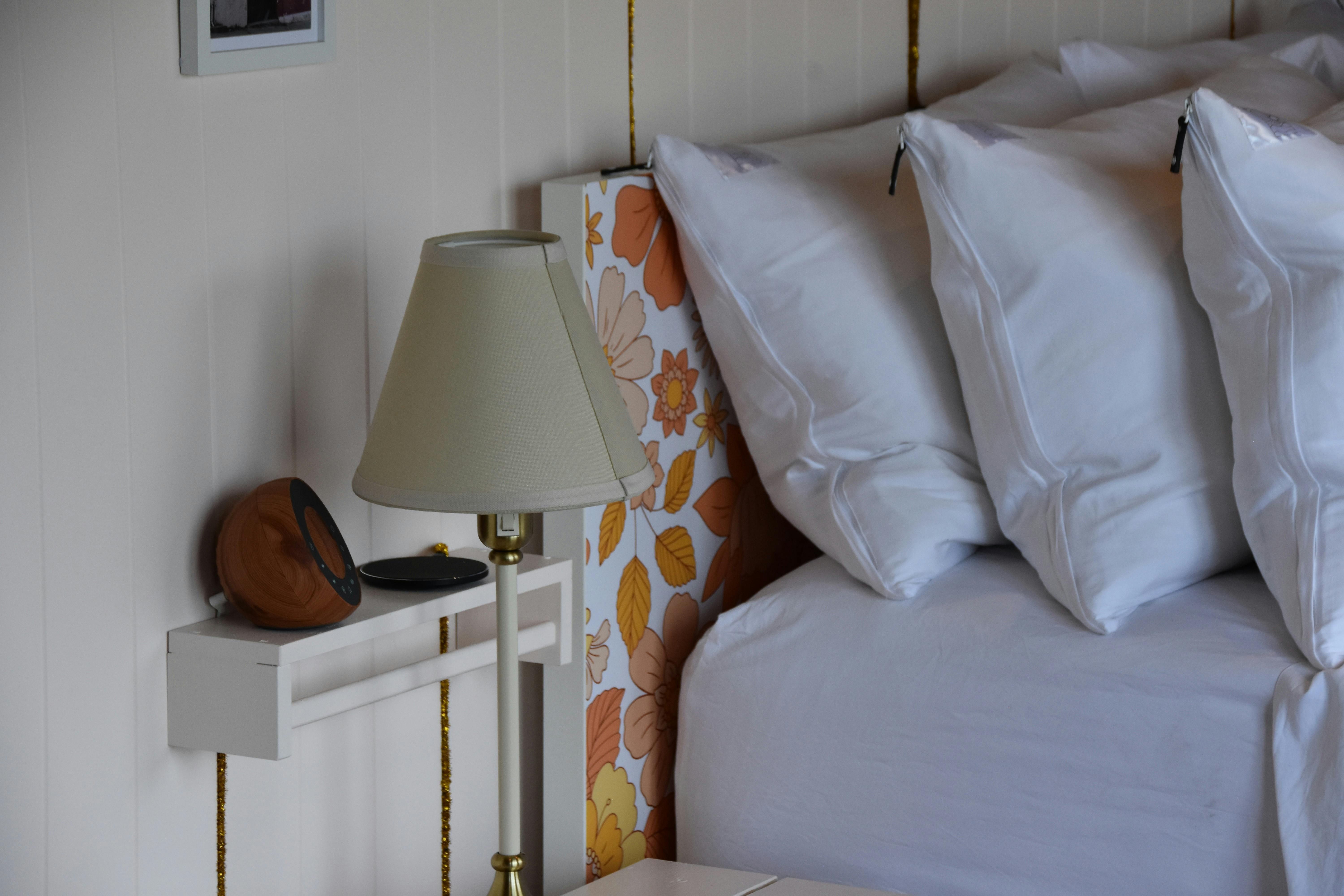 Close view of queen bed in Anwen with white linen, bedside lamp and decorative details