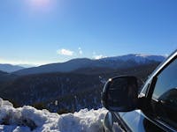 A car in the snow looking at a view of mountains