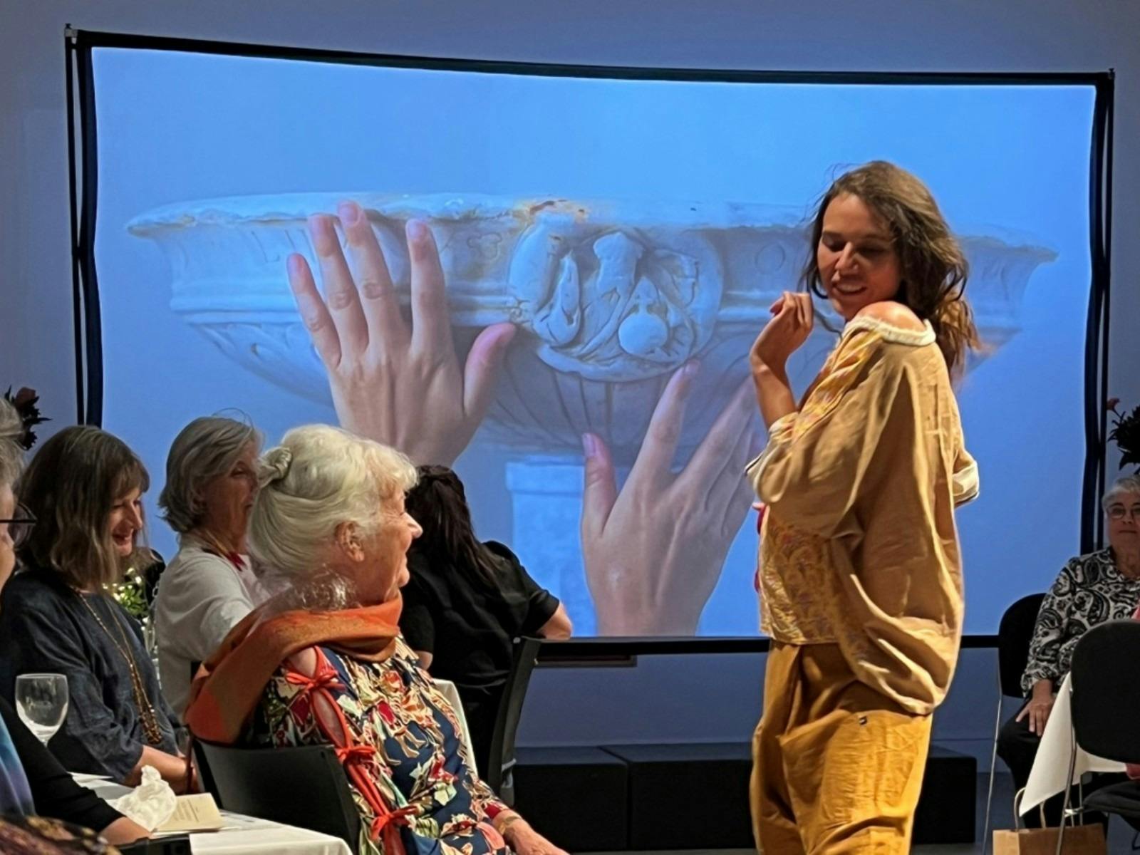 A young woman modelling an outfit with a backdrop of an exhibition installation.