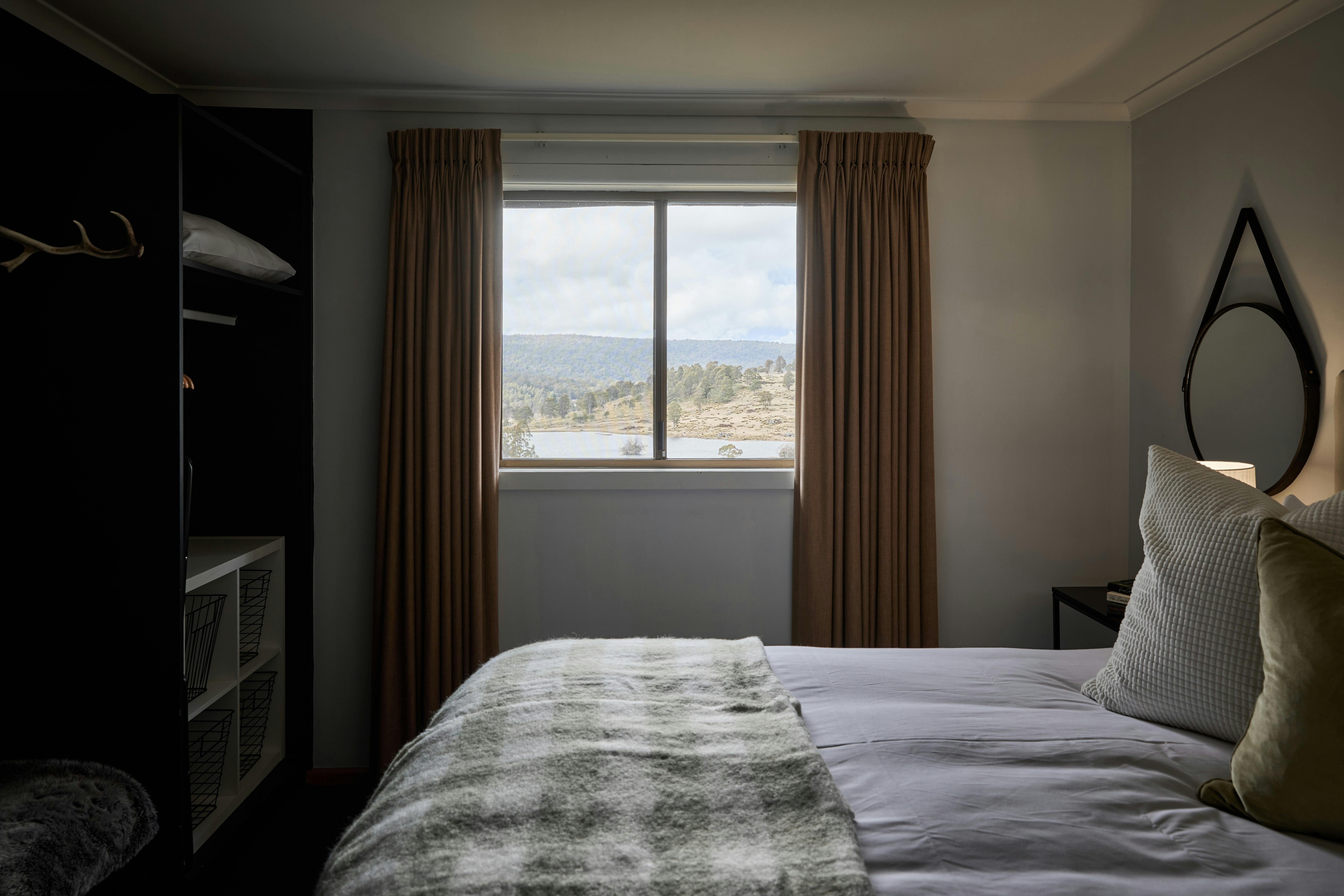 Queen bedroom with large window overlooking the bush and a lake