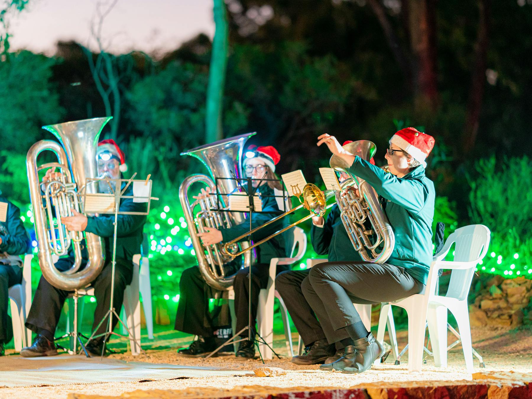 Brass band with green lights behind playing trumpets