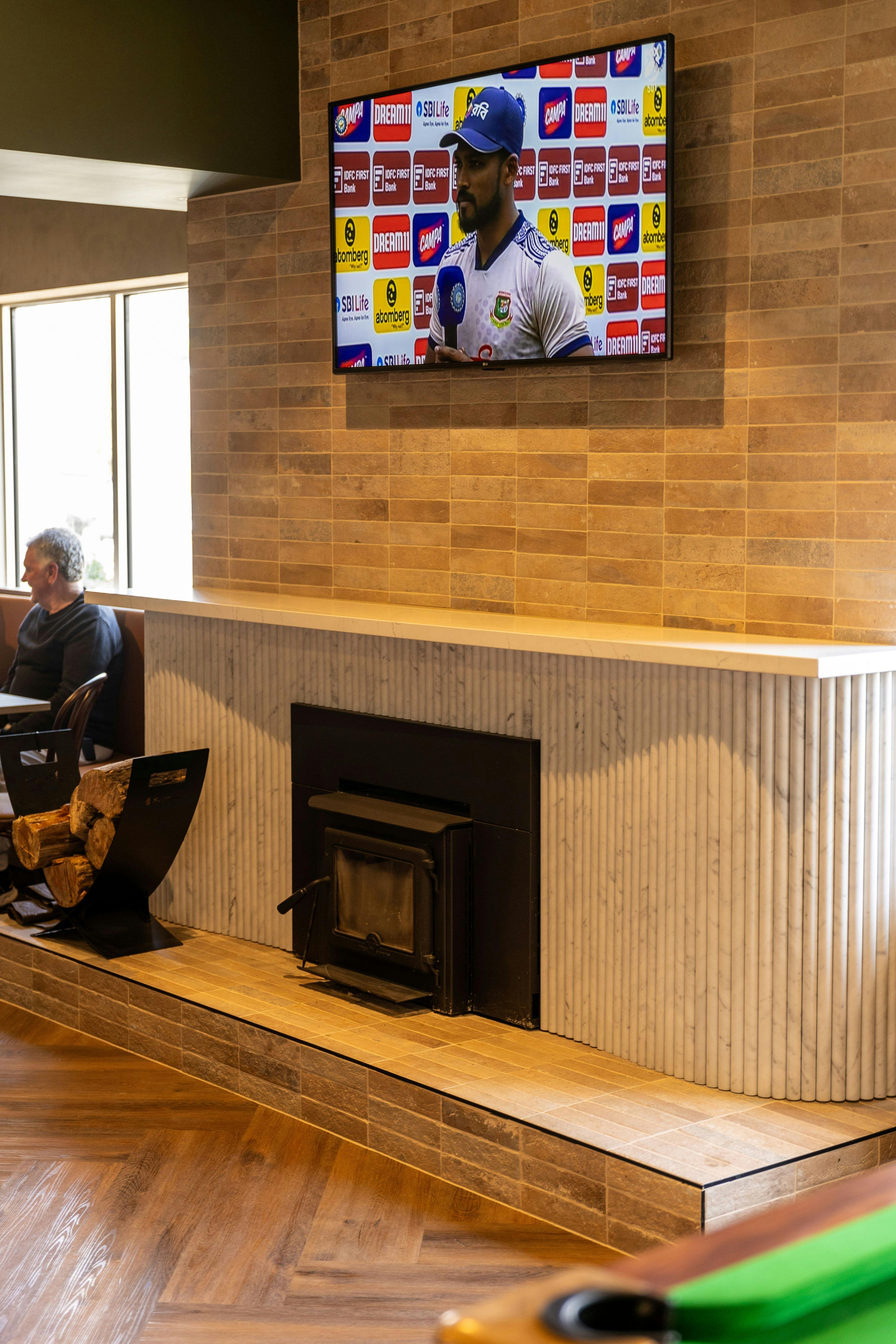 Multiple TVs showing sport and a cozy fireplace