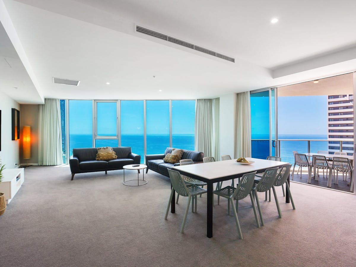 Lounge room of a 4-bedroom apartment at Hilton Surfers Paradise with a view of the blue sea behind