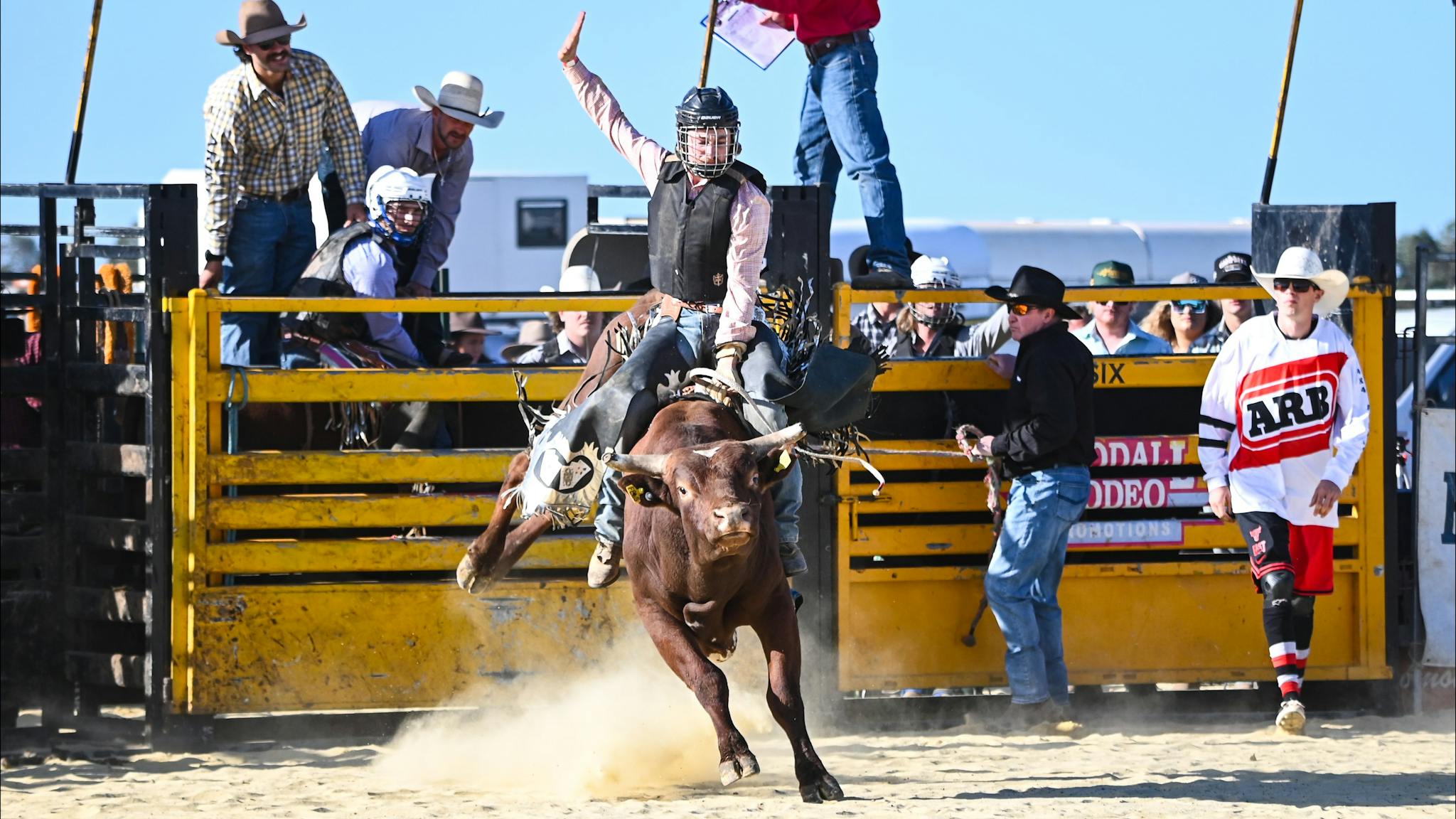 The first ride of the day a young bullrider with cowboys looking on in the background
