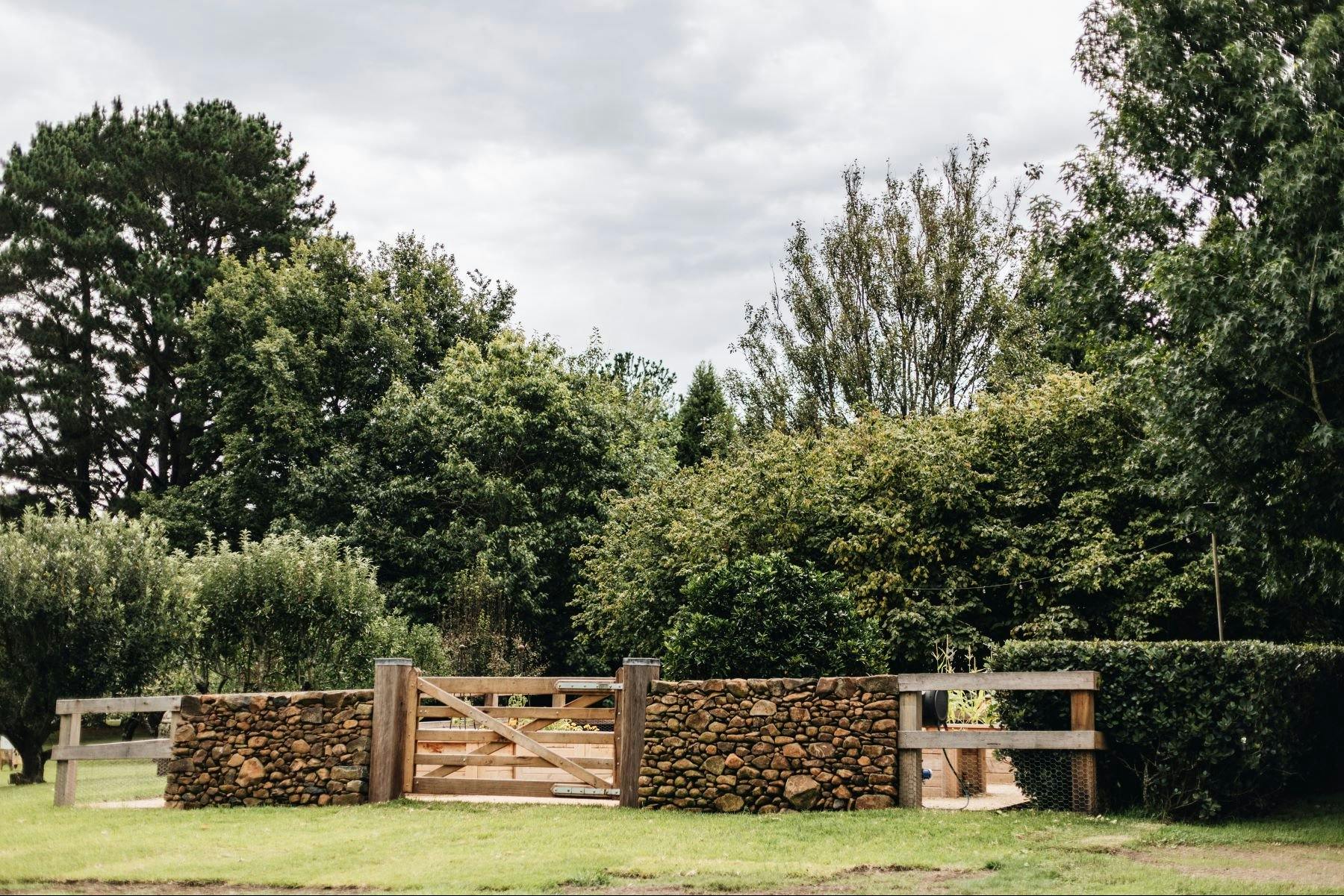 두툼한 돌담과 나무 대문이 있는 채소밭과 과수원