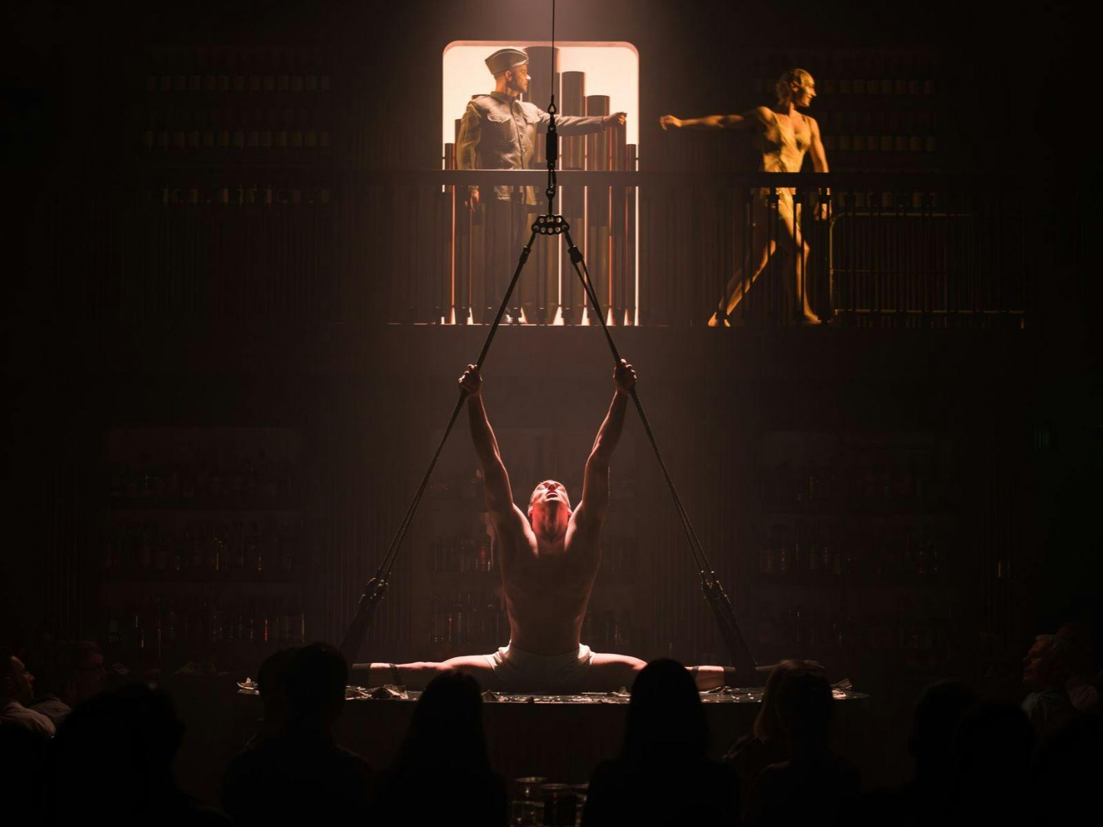 A performer does the splits with dim lighting.