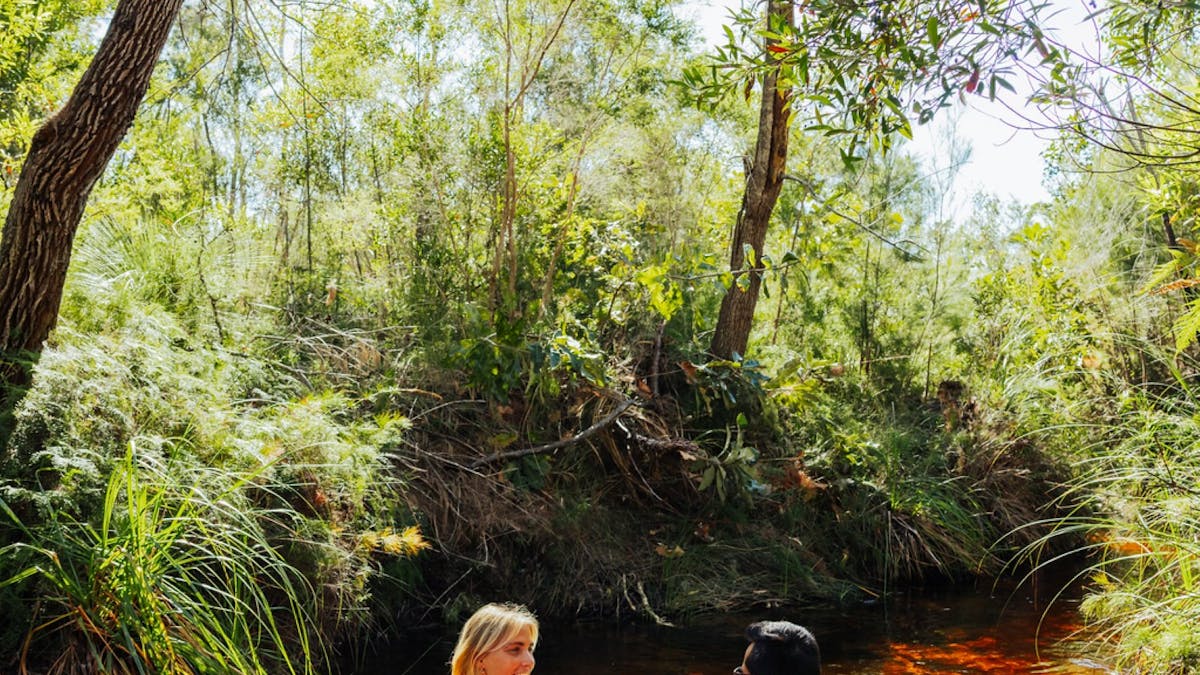 Two people on the red waters of Seary's Creek with a floaty