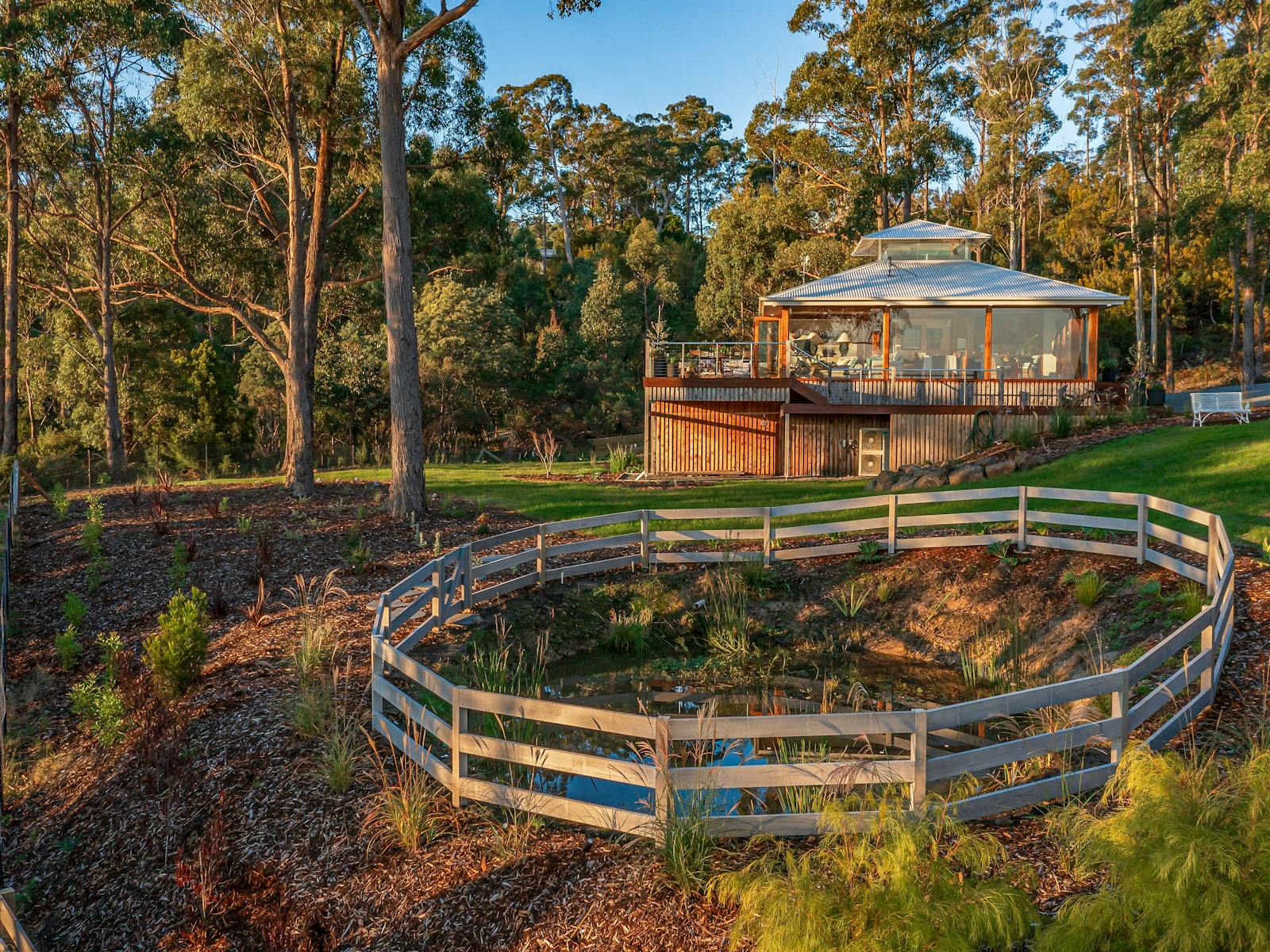 An golden hour photo of the Huon River Hideaway bushland property with the house in the background