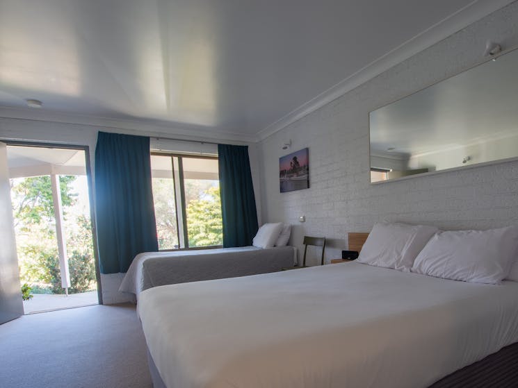 A standard twin room with queen and single bed, dining area and kitchenette facility.