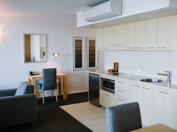 A kitchenette featuring bar fridge, microwave, sink, air-con, a desk and dining area.