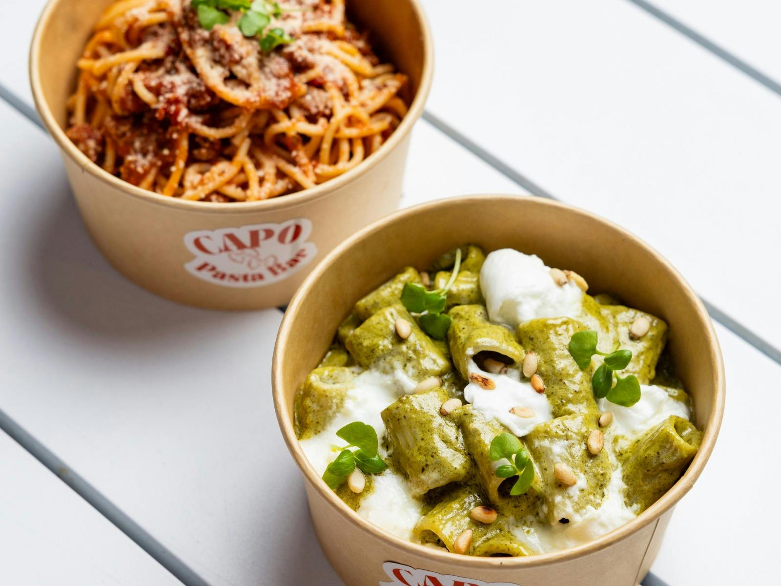 外帶義大利麵碗的特寫，配上肉醬義大利麵和香蒜醬通心粉