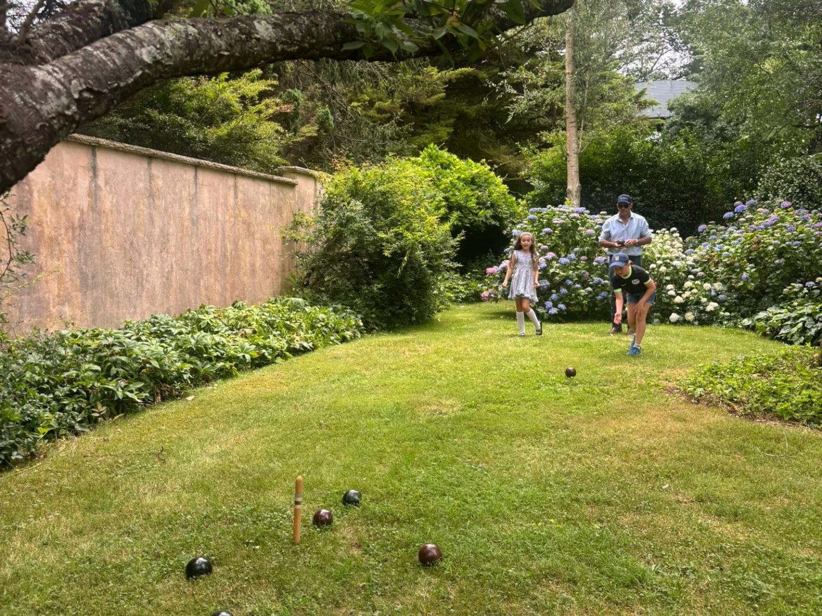 Two children and an adult playing lawn games among the walled garden.