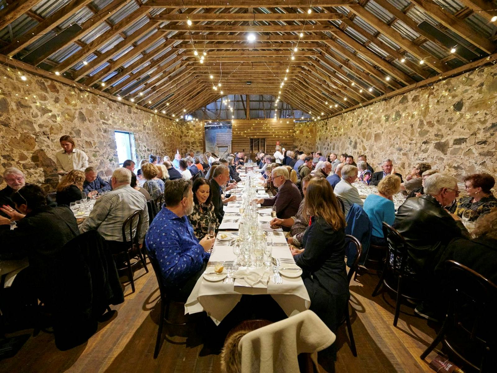 Long tables are filled with customers, enjoying the Taste the Region dinner, in historic venue.
