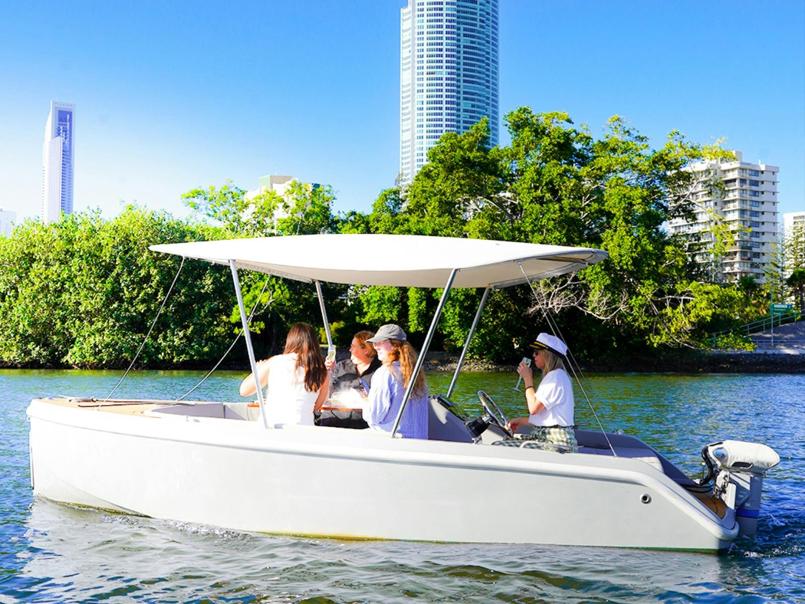 Group of guests relaxing aboard a self-drive GoBoat with Gold Coast skyline views in the background.