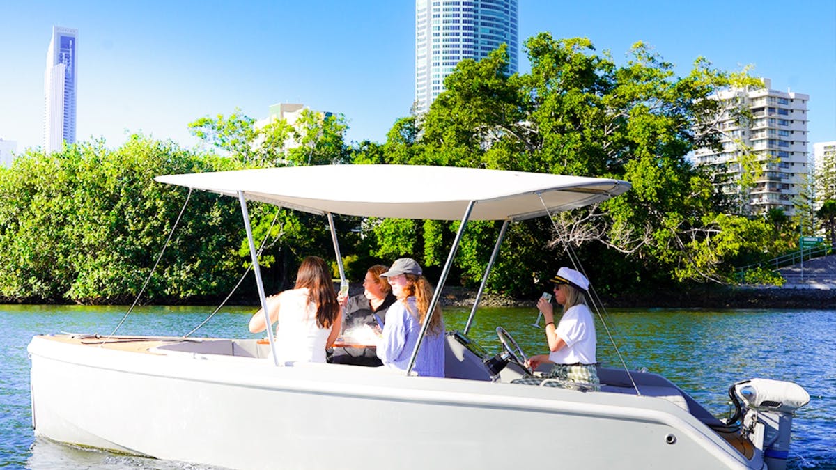 Group of guests relaxing aboard a self-drive GoBoat with Gold Coast skyline views in the background.