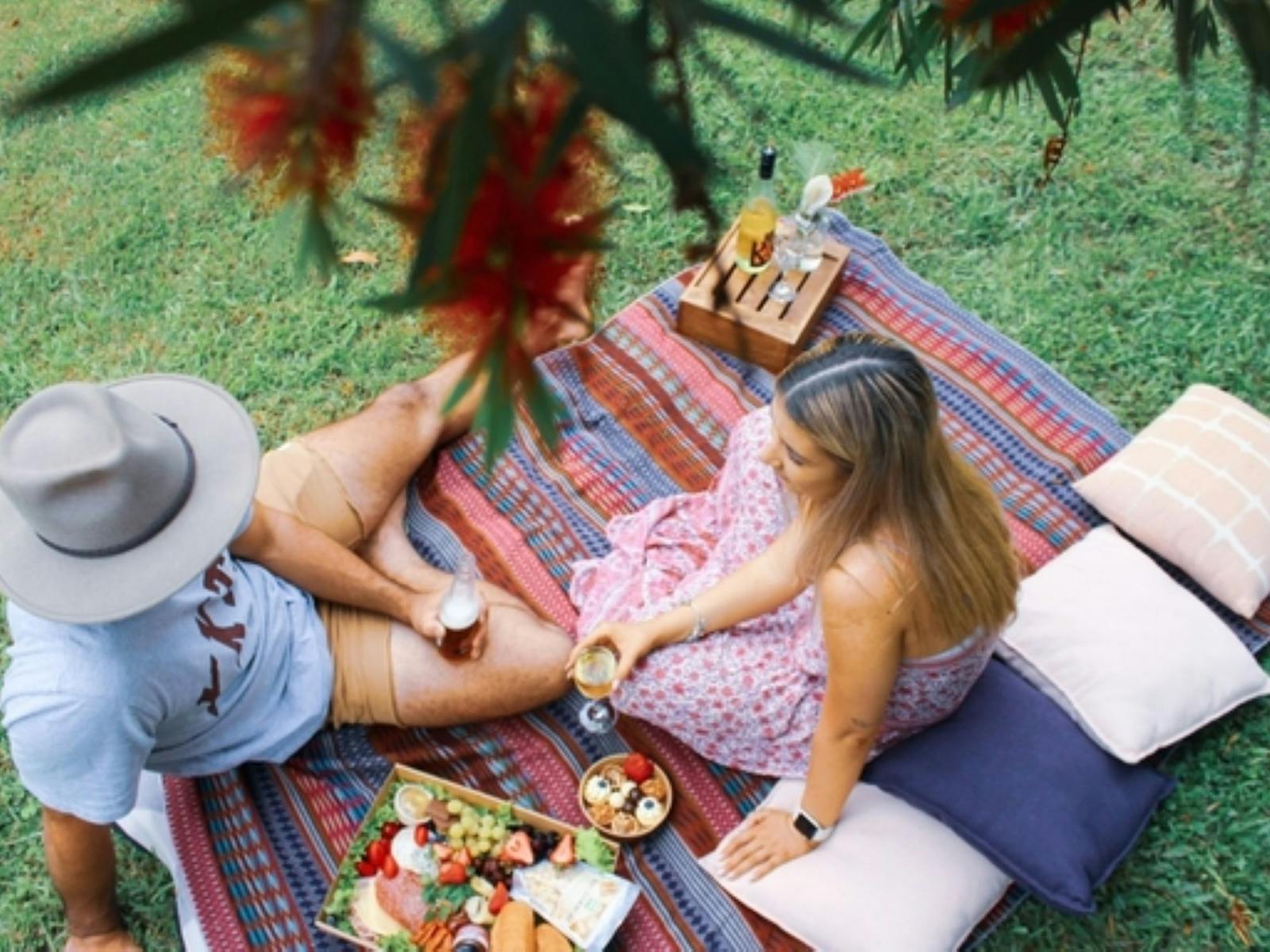 Aerial image of a couple sitting on a rug enjoying a picnic of farm fresh produce