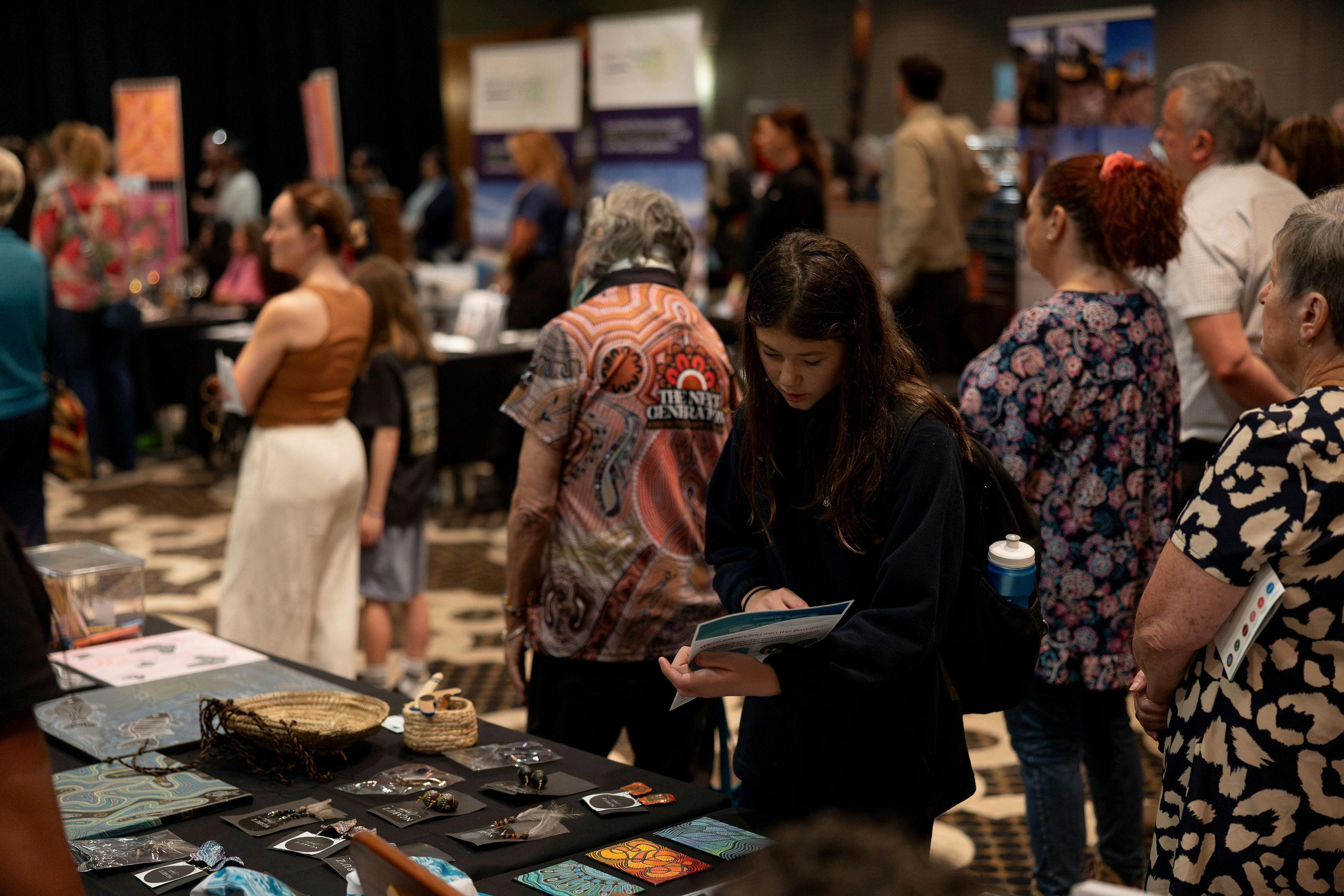 Image of a woman looking at items on a table at the Illawarra Indigenous Business Expo 2025