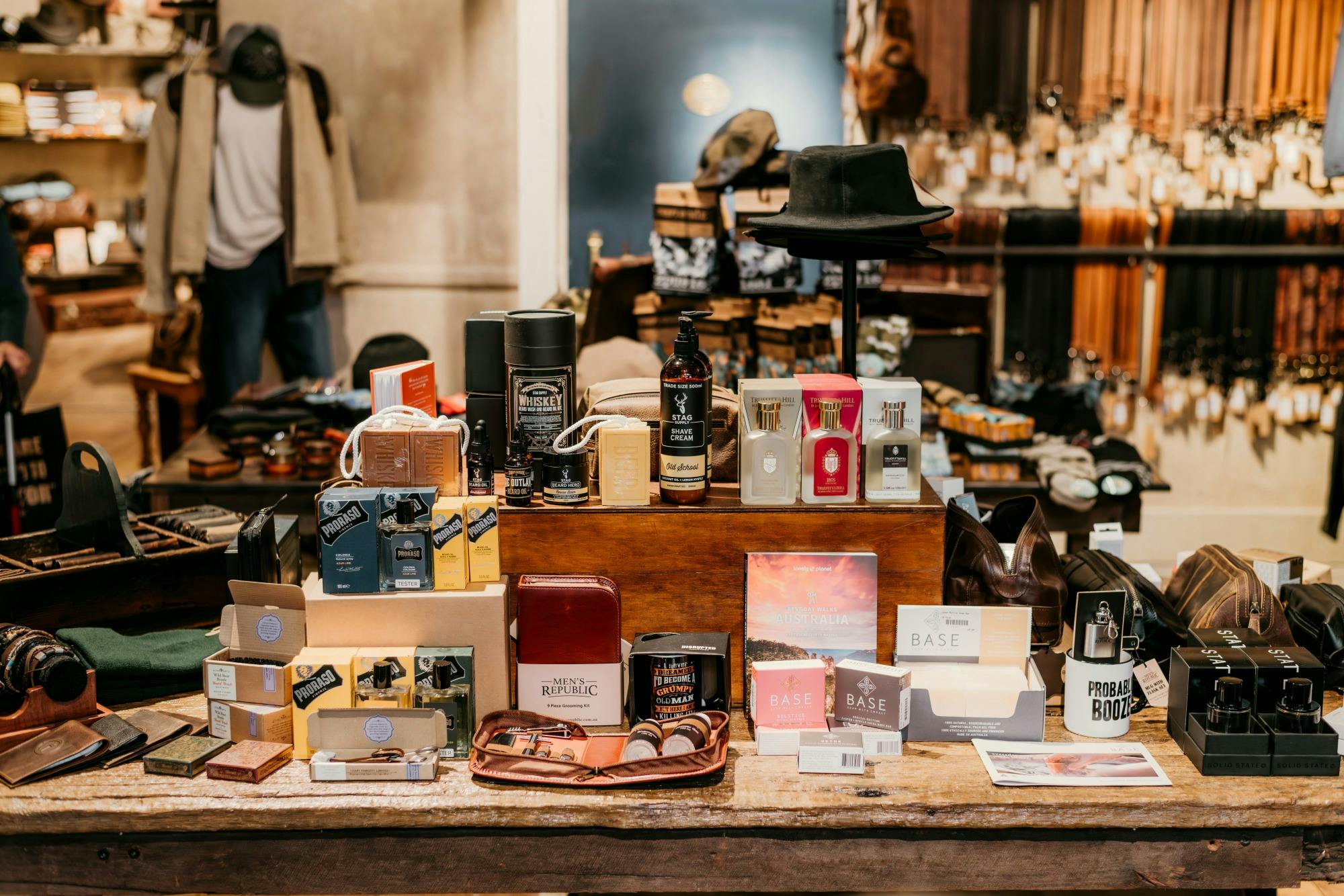 Table of men's grooming gifts: cologne, beard oil, soaps and leather toiletry bags
