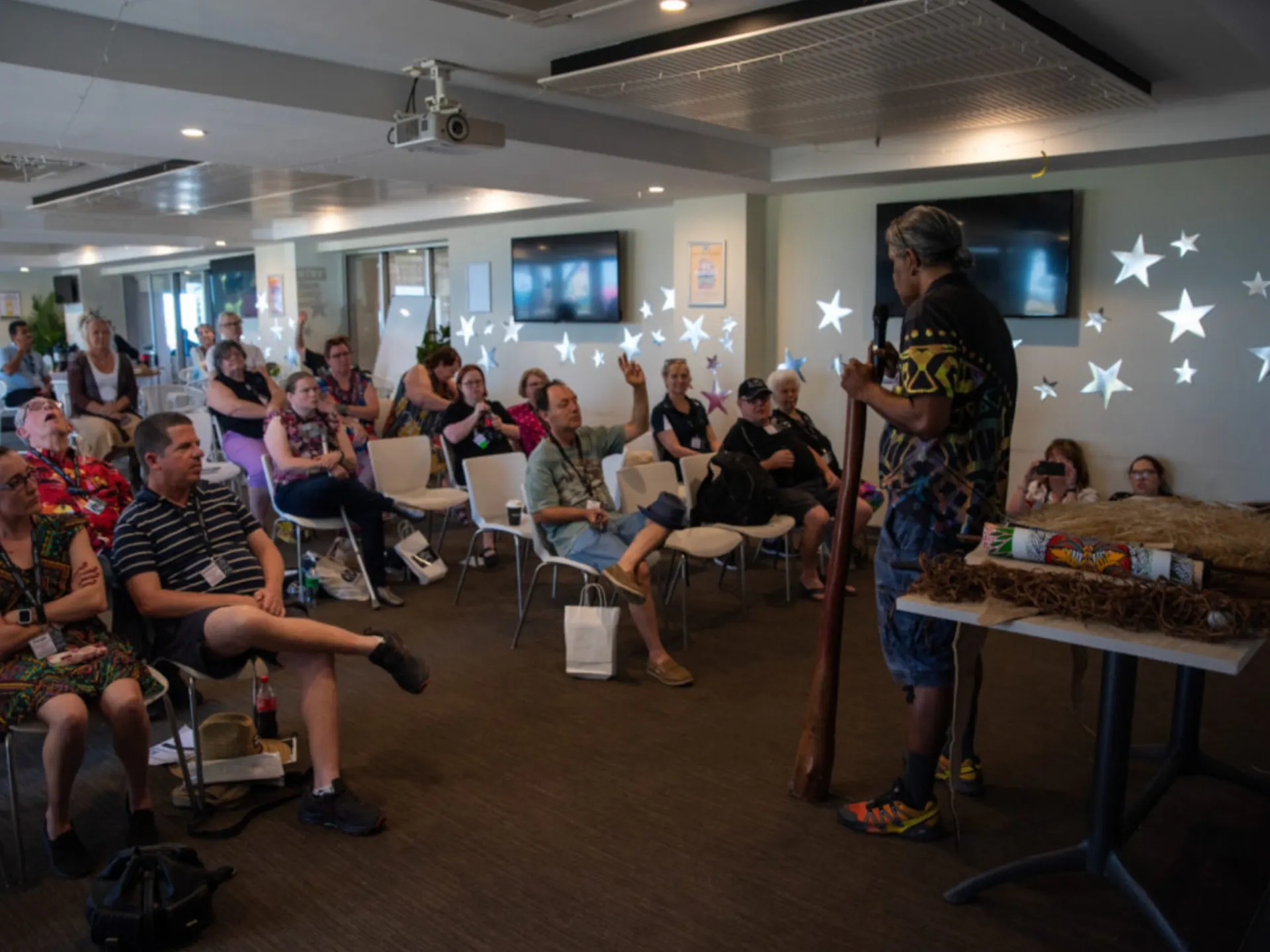 A room of people listening to a speaker