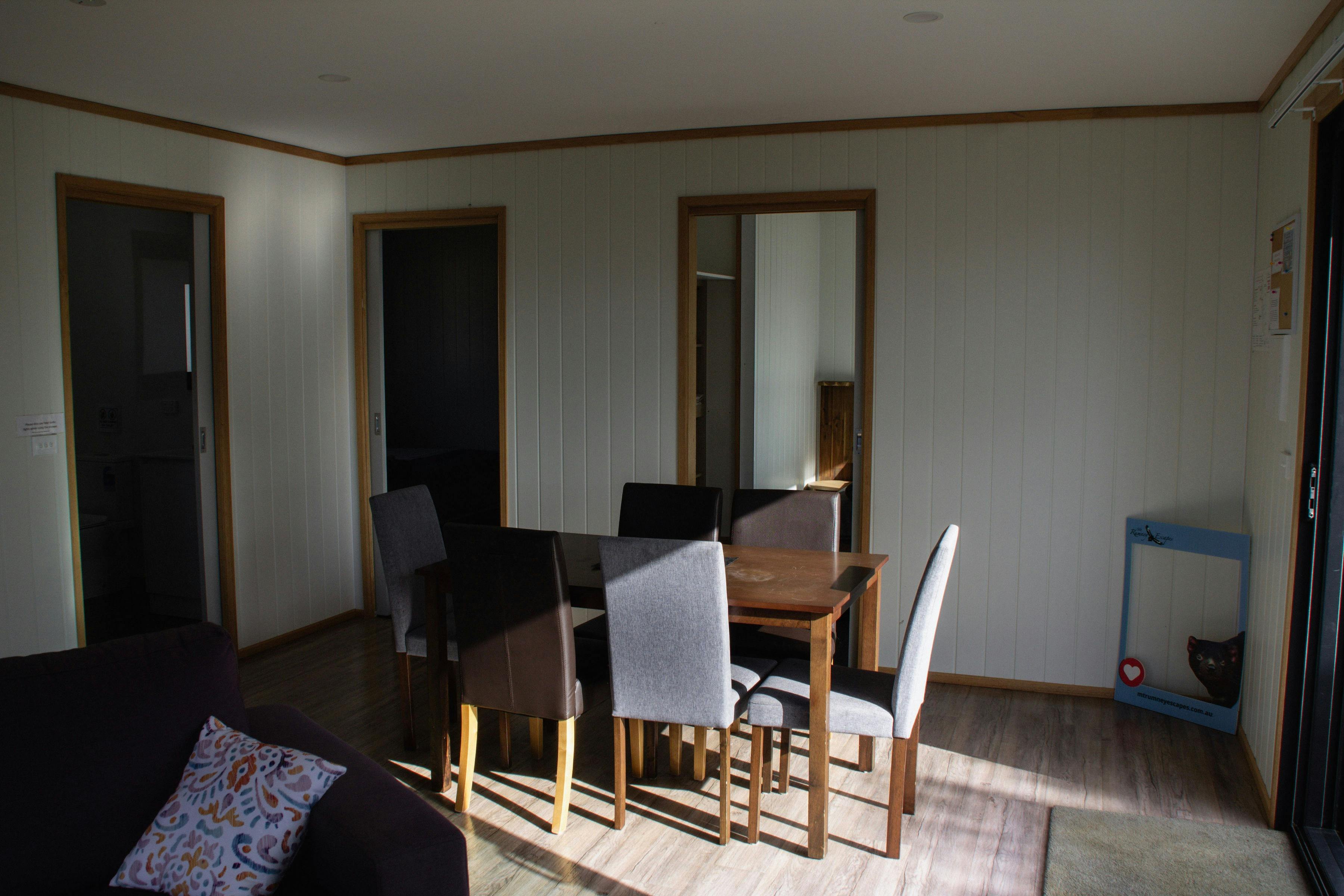 Living and dining area inside Devil House with dining table, chairs, sofa and large windows