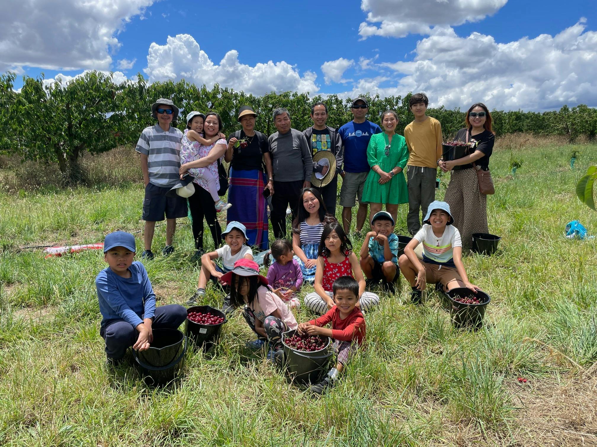 Extended family group having fun spending the day in the orchard and picking fruit