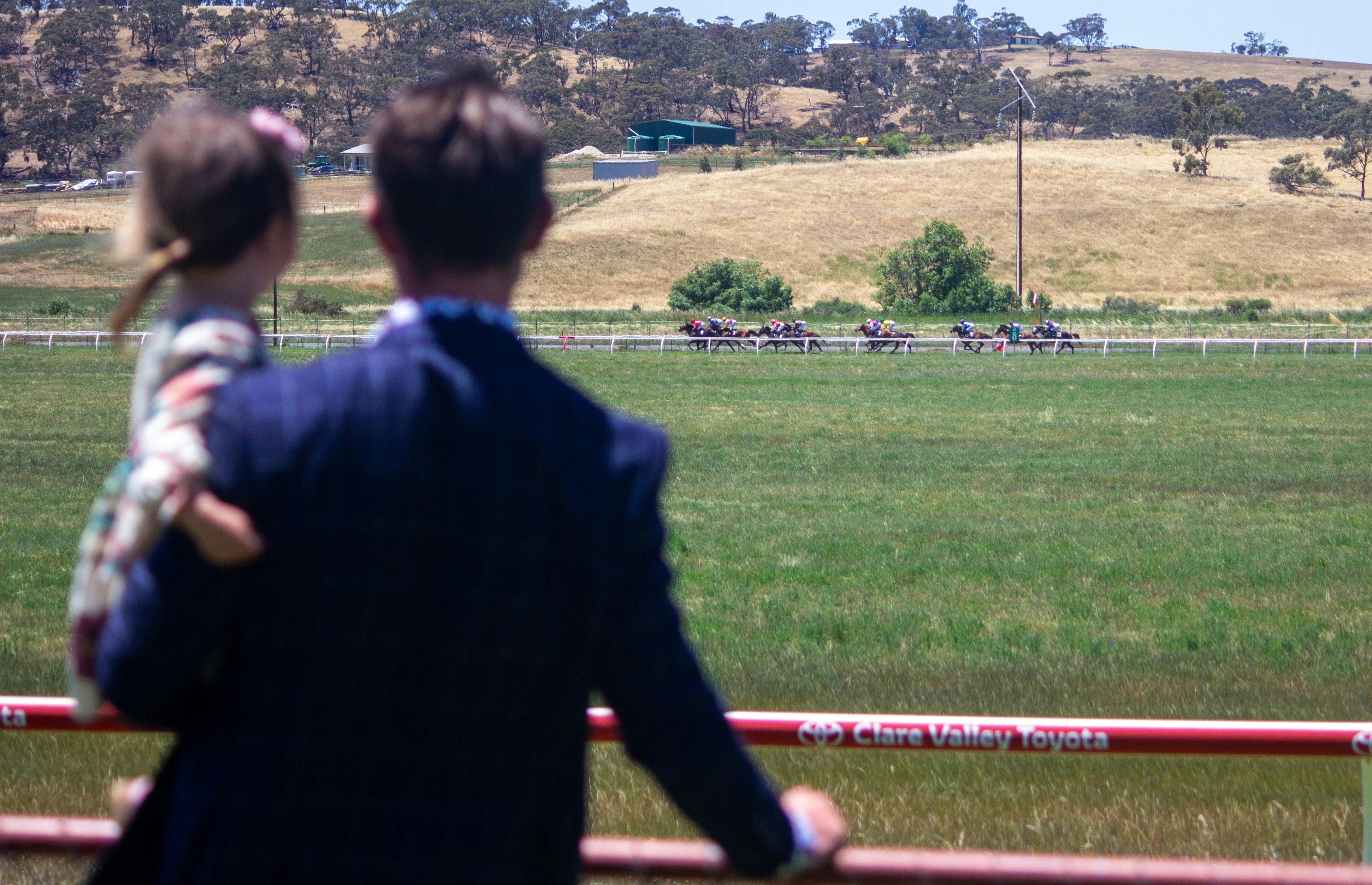 Man and girl watch horses race