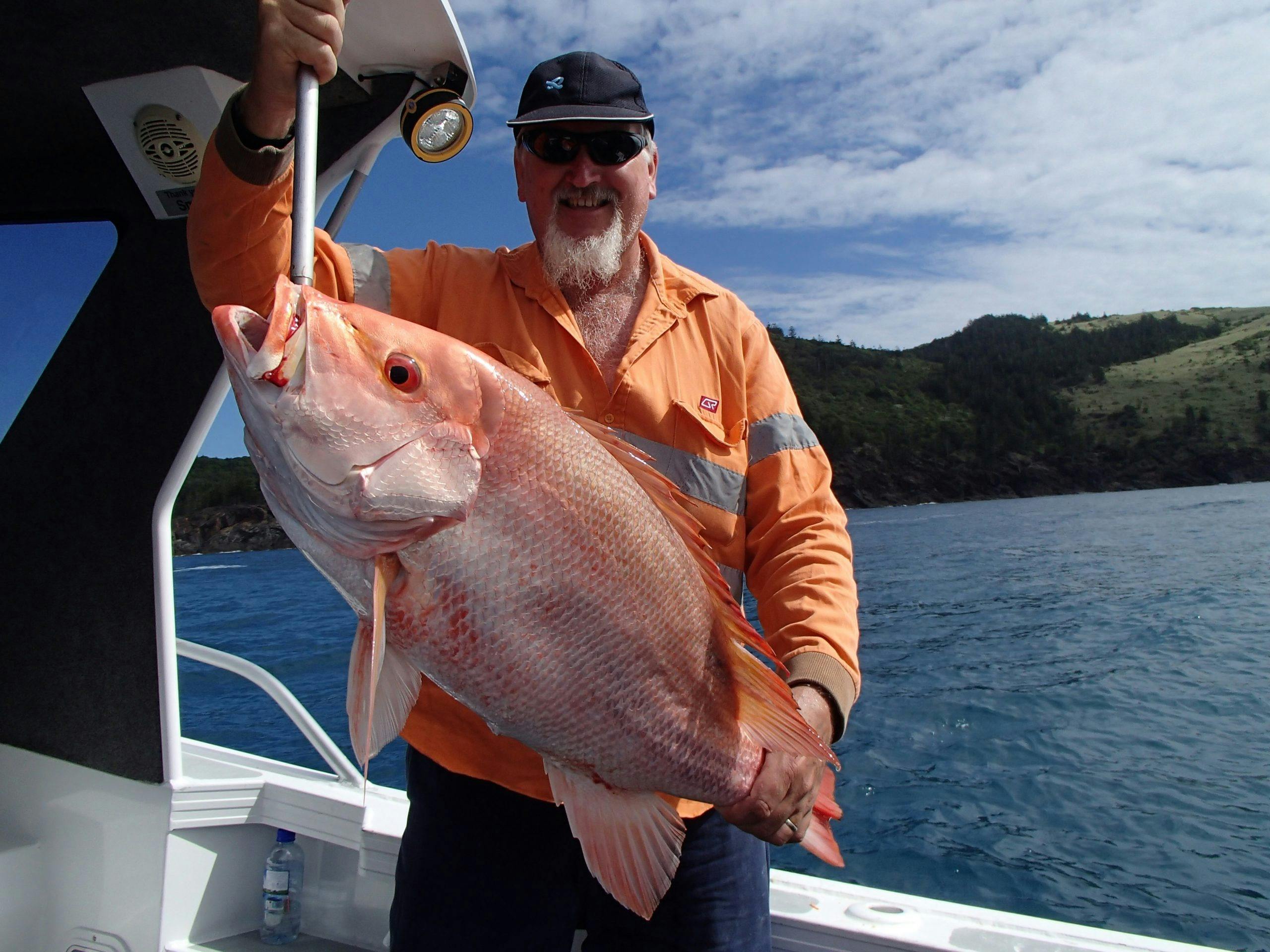 Keen angler in the boat, holding up a very large red throat emperor.