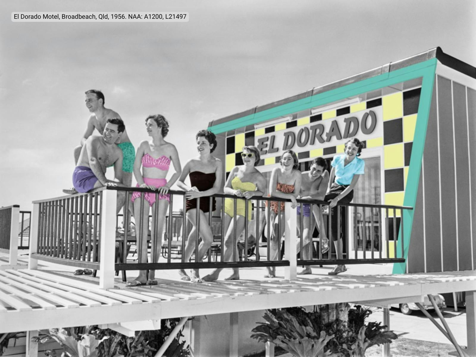 A group of people in swimwear stand on a balcony in front of a motel
