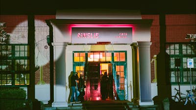 The front facade of the Ainslie Arts Centre, lit up with projected lights and shapes.