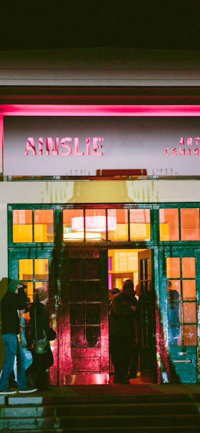 The front facade of the Ainslie Arts Centre, lit up with projected lights and shapes.
