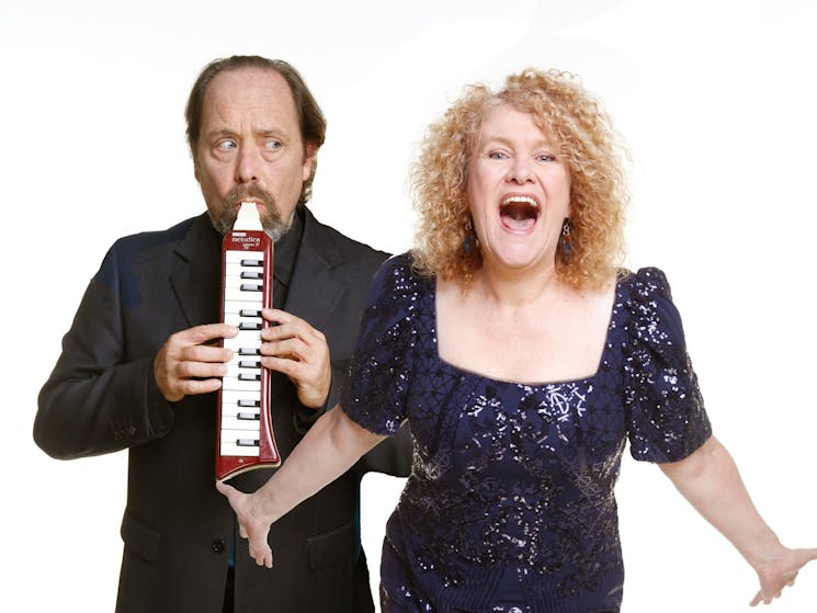 Melissa Langton and Mark Jones singing to the camera and playing a wind keyboard
