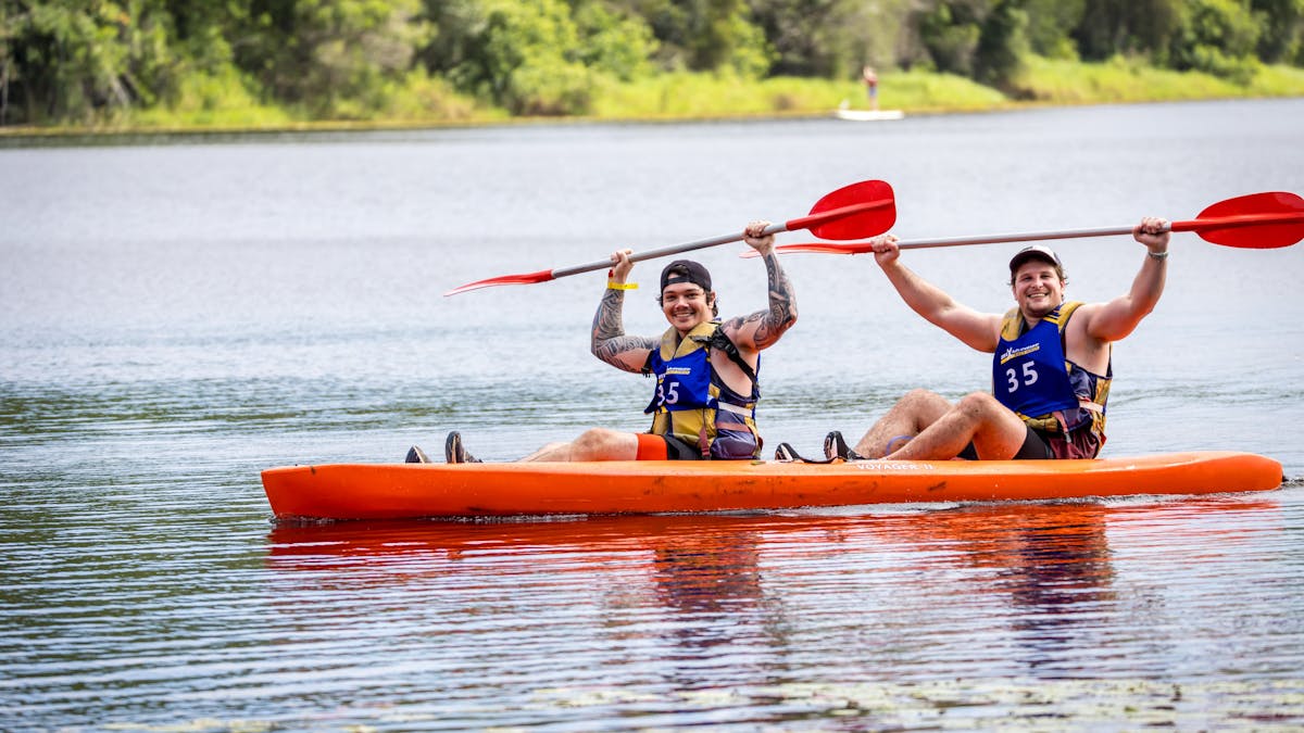 Two kayakers raise their paddles overhead triumphantly