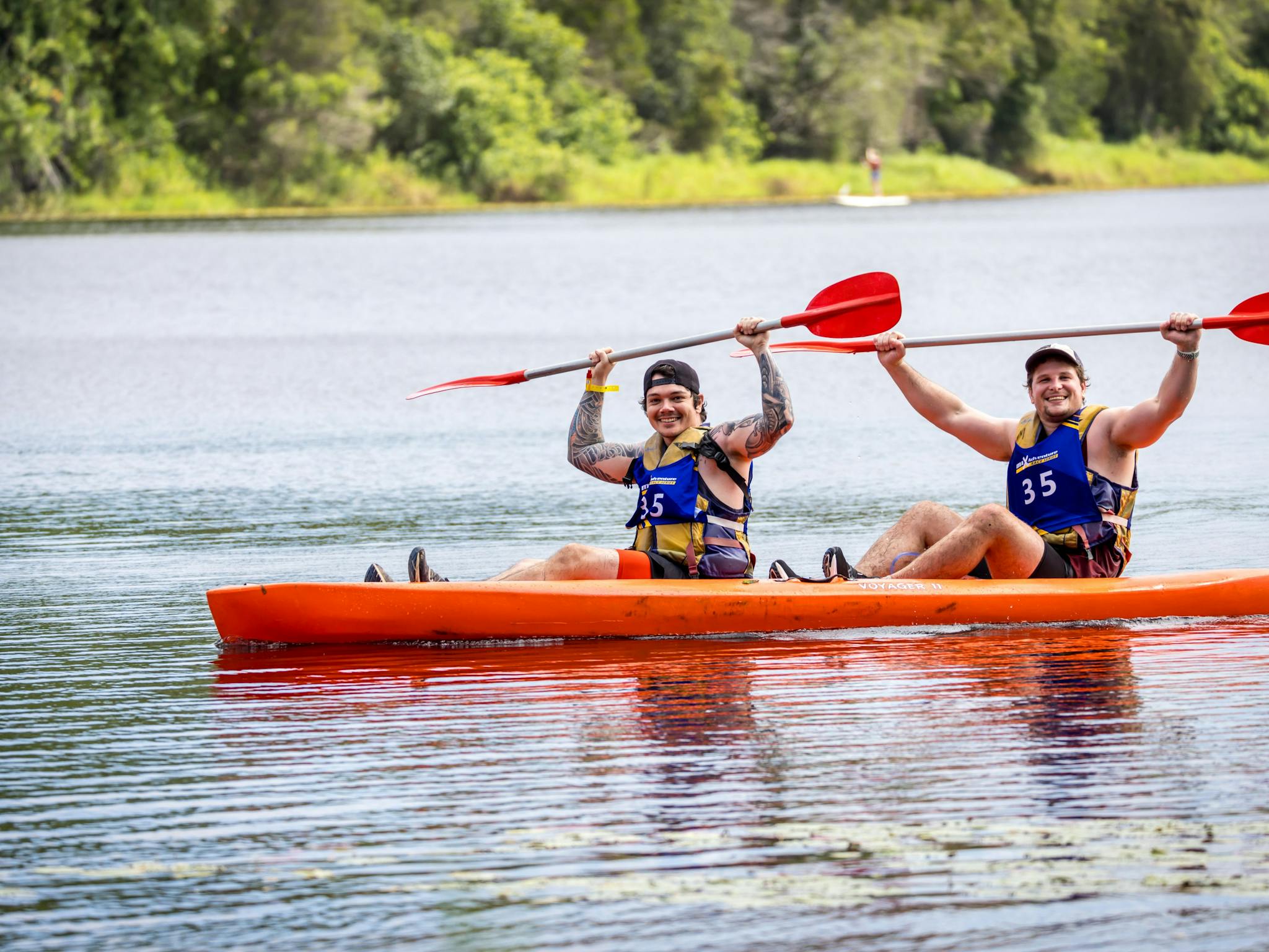 Two kayakers raise their paddles overhead triumphantly Two kayakers raise their paddles overhead triumphantly