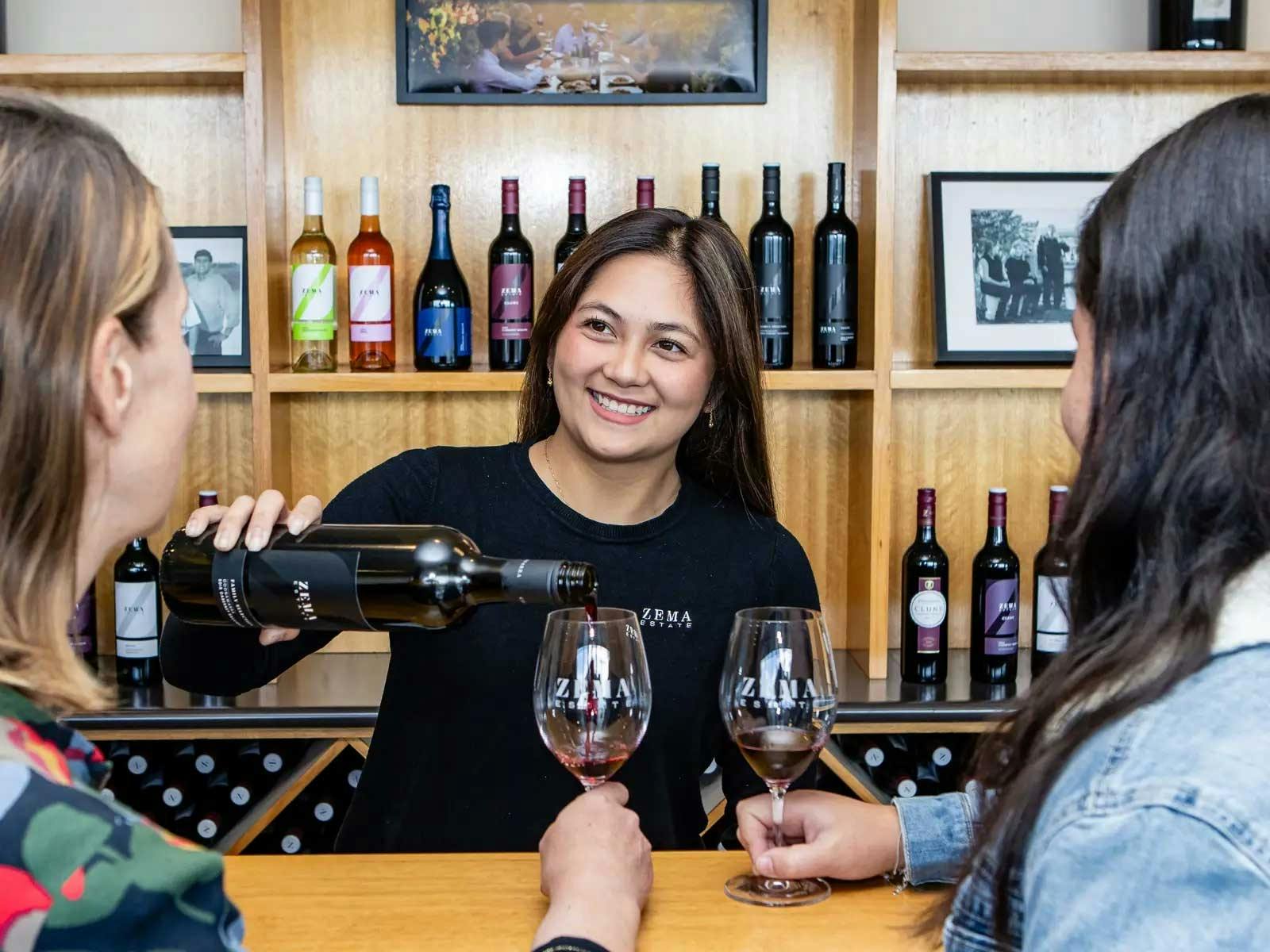 lady pours red wine at winery cellar door