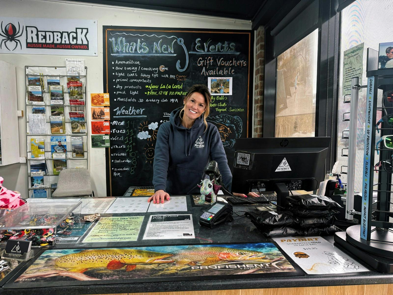 A woman smiling standing behind a shop register