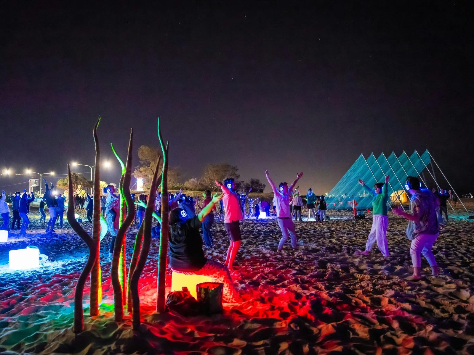 100s of people dancing on the beach at Silent Disco Under the Stars at SWELL Sculpture Festival