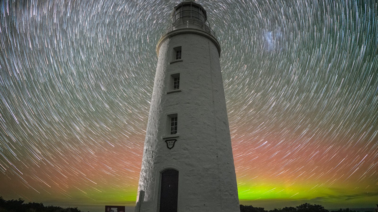 Cape Bruny Lighthouse star trail back-lit by Aurora australis