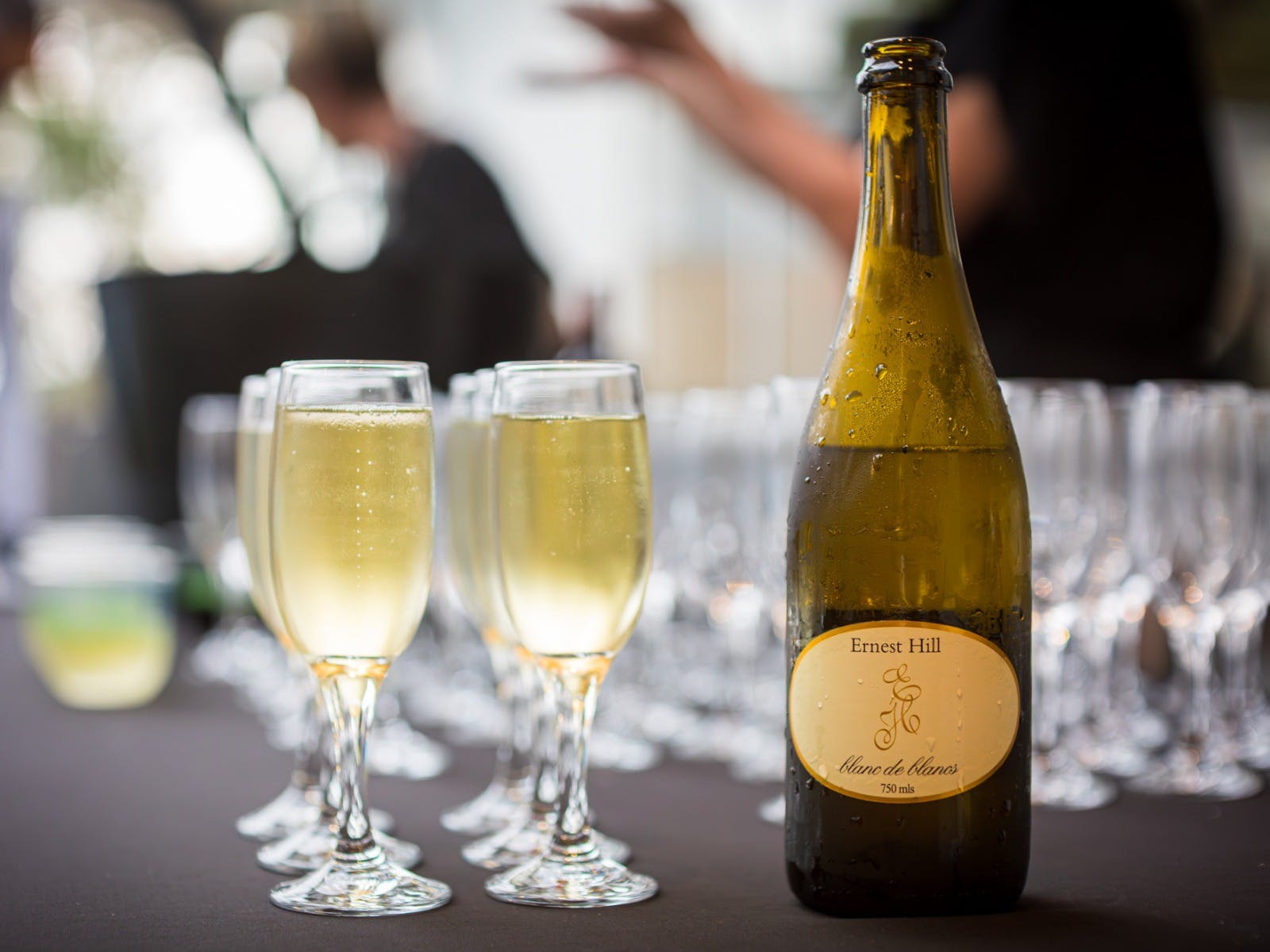 Glasses of sparkling wine next to a bottle of Ernest Hill sparking wine