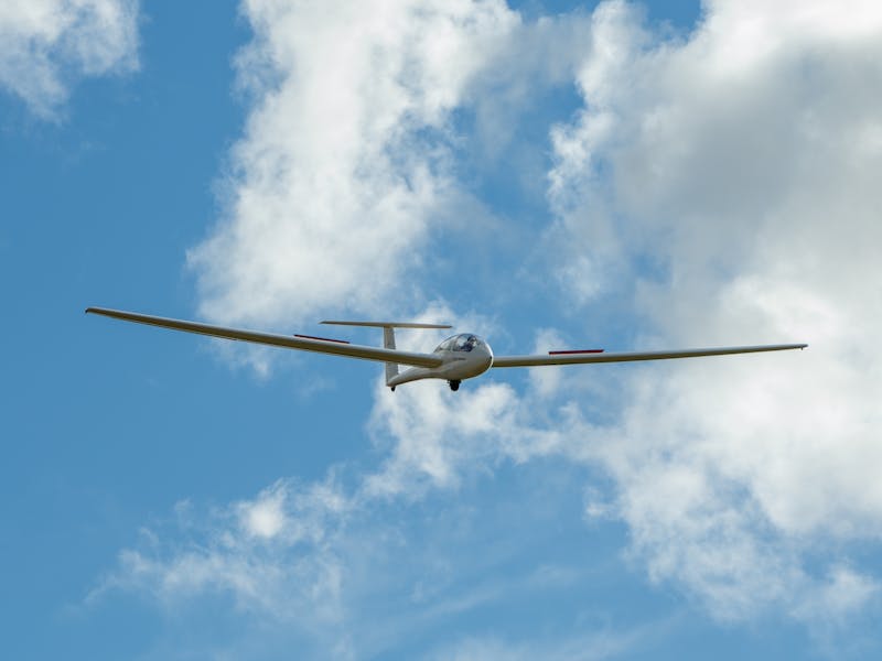 Non powered Glider in the sky soaring above the Tasmania Gliding Club clouds and sky in the backgrou