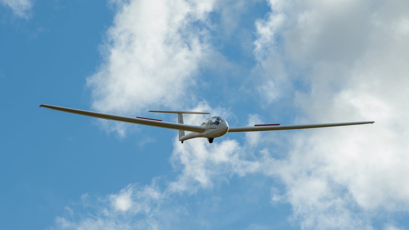 Non powered Glider in sky with clouds above the Tasmania Gliding Club