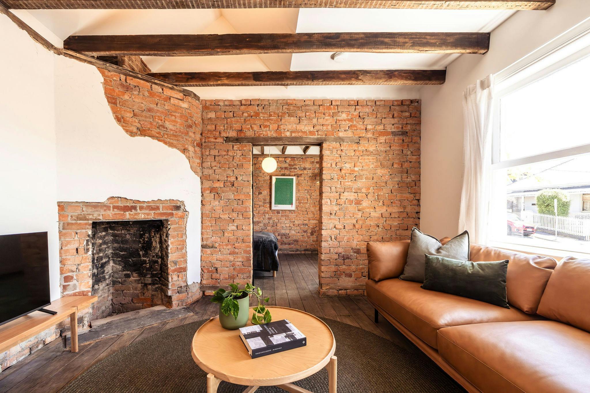 Image showing the living room with fireplace, leather couch and exposed brock and beams
