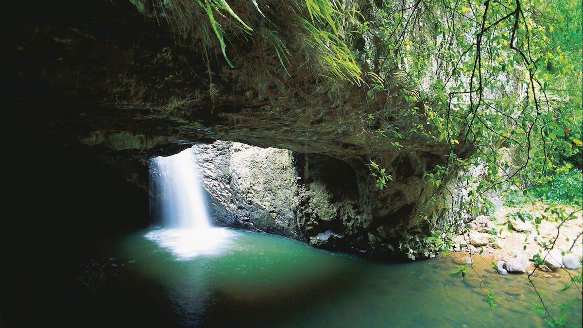 White water cascades down a rockface into a green rockpool