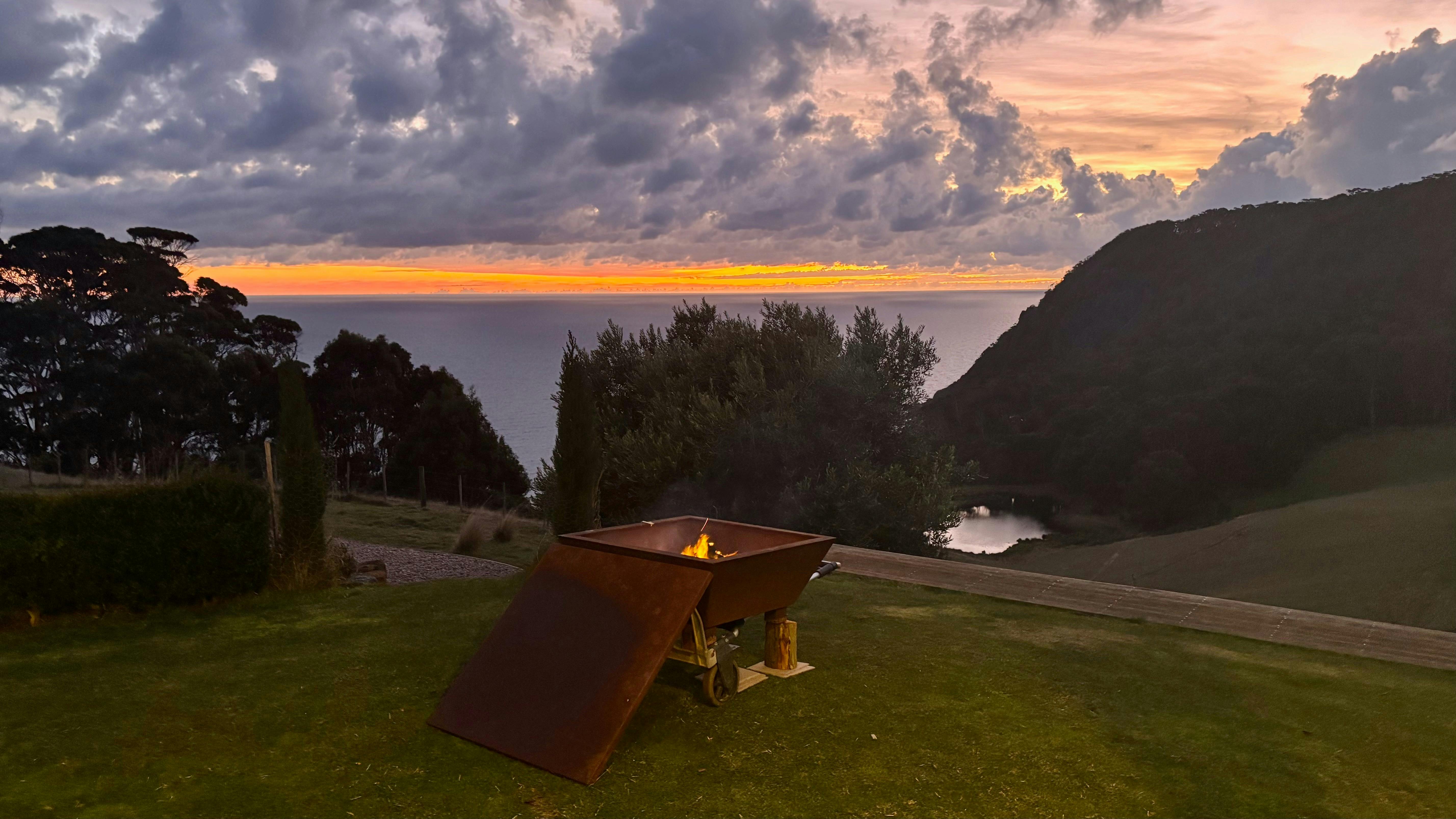 Firepit burning, as sun rises, in the paddock overlooking Bass Strait