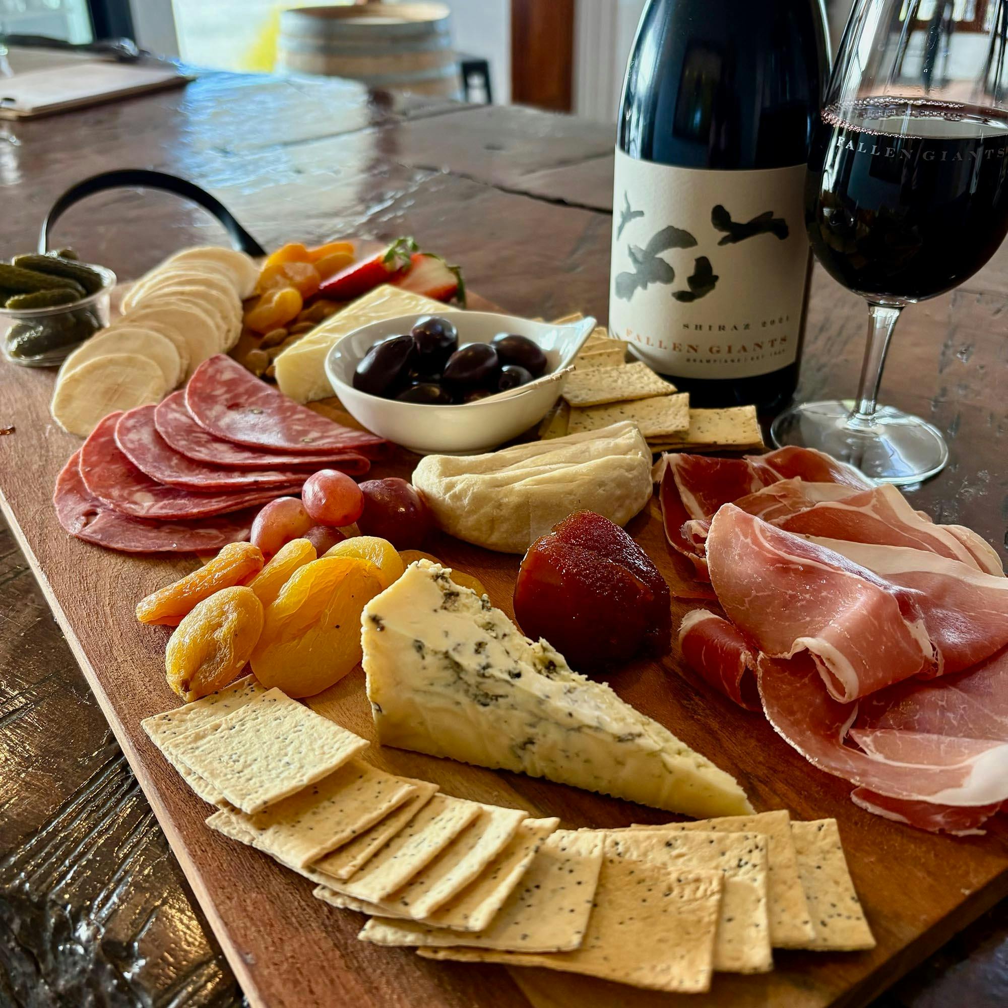 A cheese board at Fallen Giants, bottle and glass of wine