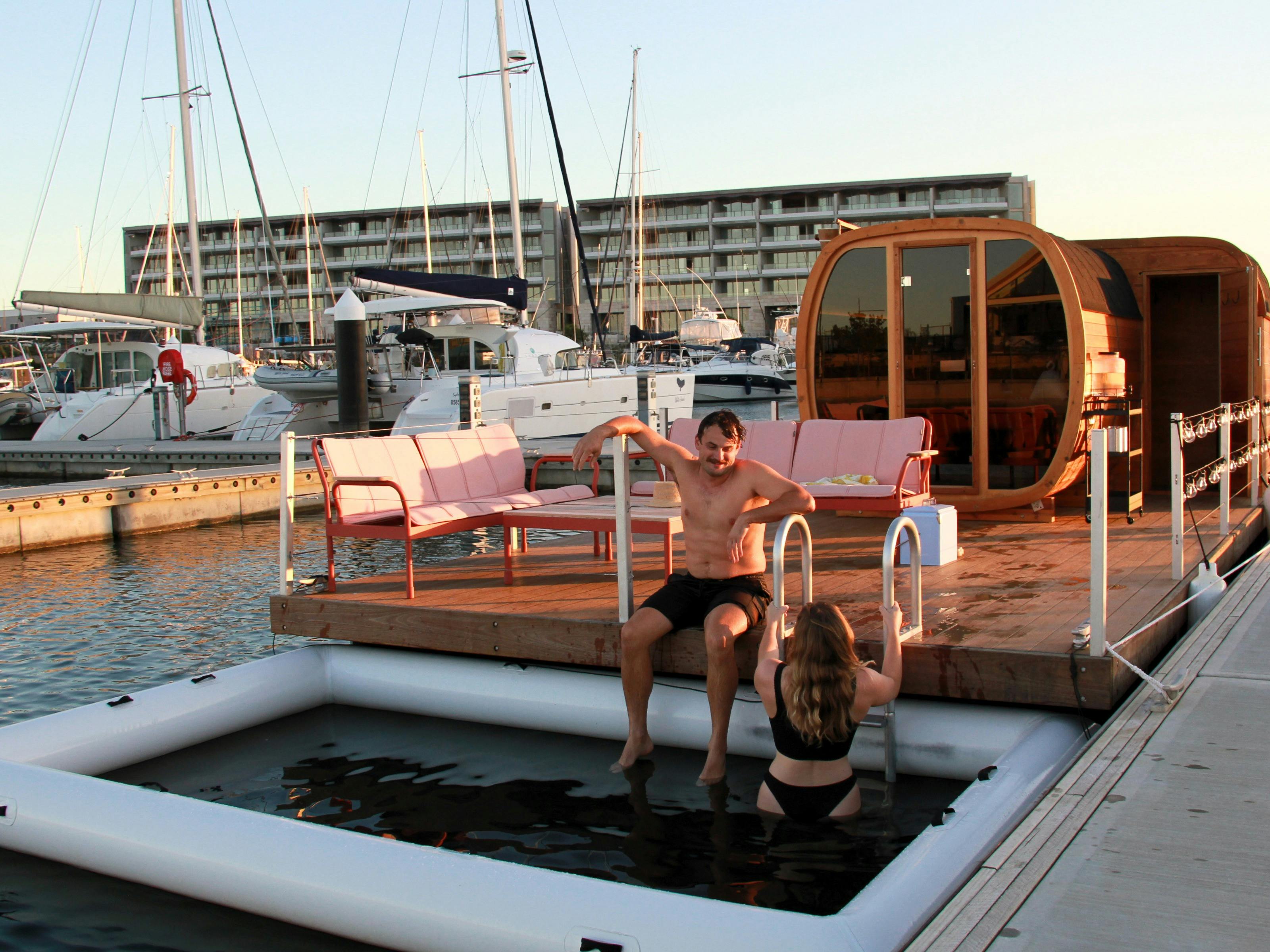 View of the floating sauna in the evening  with people sitting on the pontoon